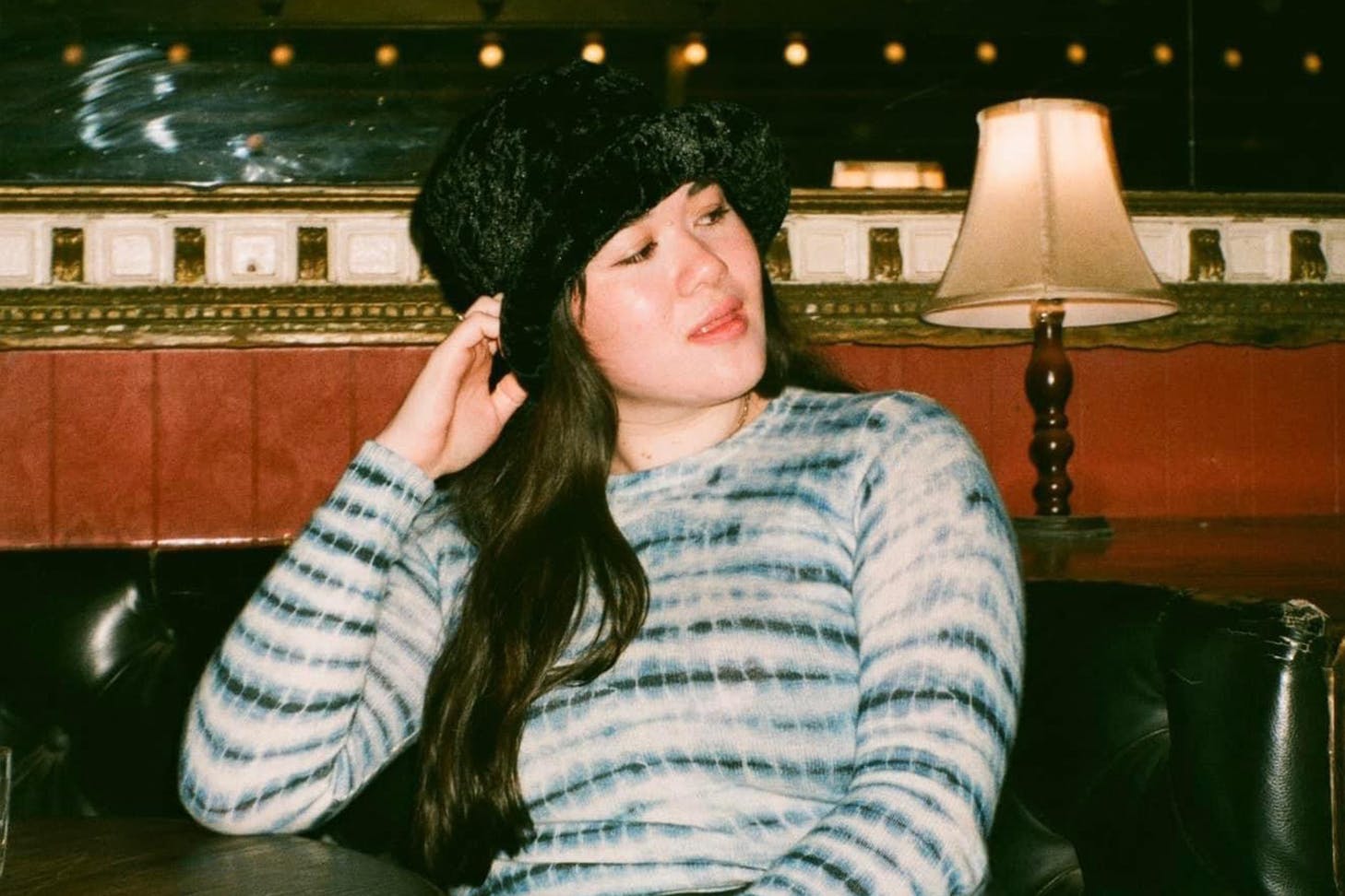 Woman sitting at a bar with a black fluffy hat on